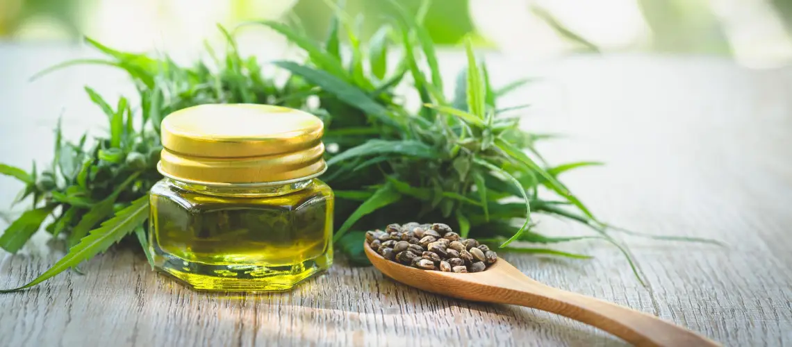 A person holding a herbal tincture bottle with fresh medicinal plants in the background